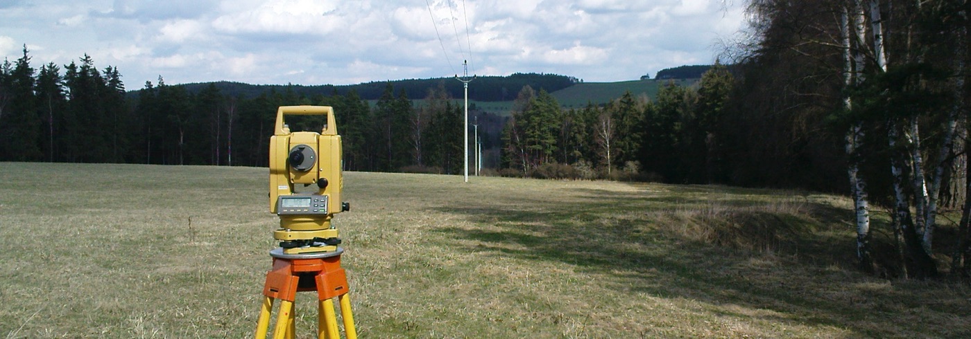 Geodetická totální stanice na stativu při měření v terénu